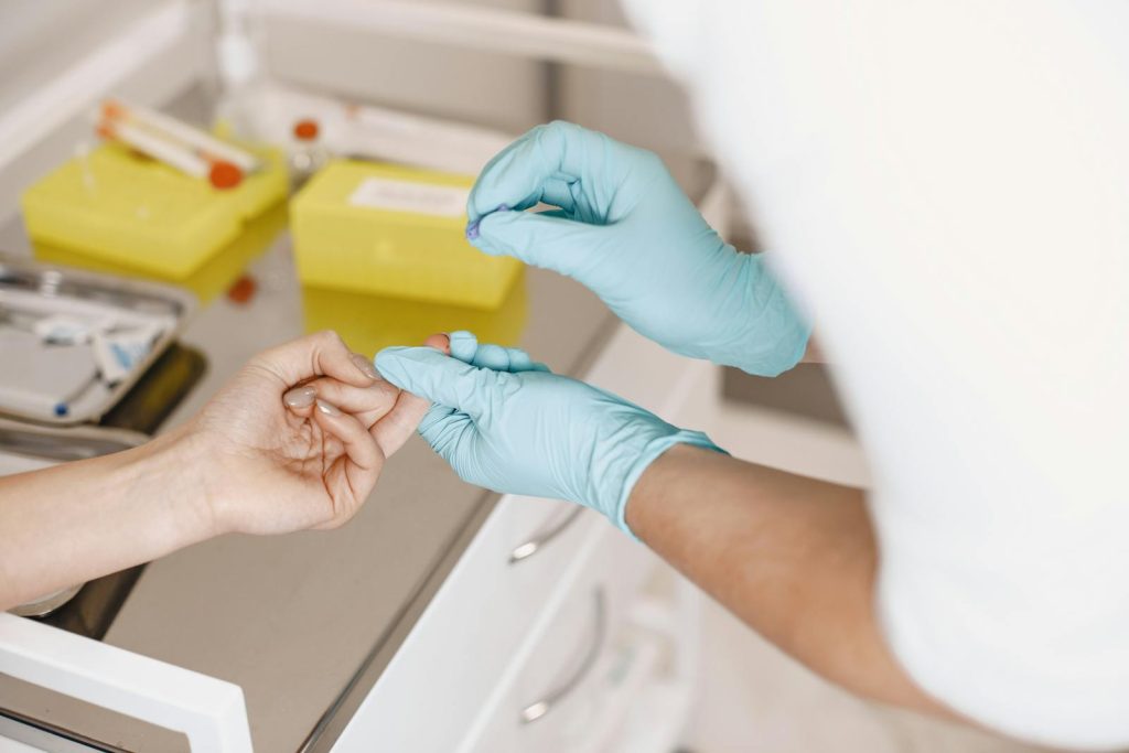 A healthcare professional wearing gloves takes a blood sample from a patient. Medical setting.