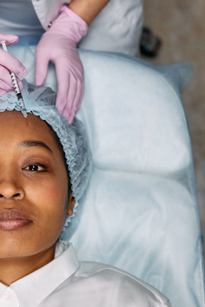 A woman receiving a cosmetic forehead injection in a clinical setting.