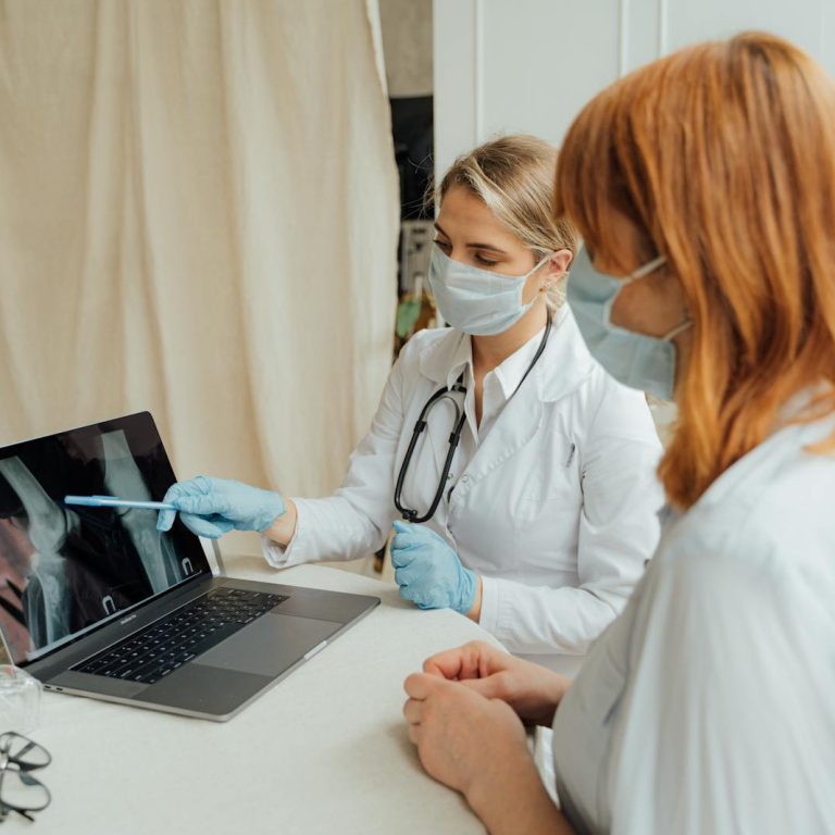 Doctor explains X-ray results to patient using a laptop in a clinic setting.
