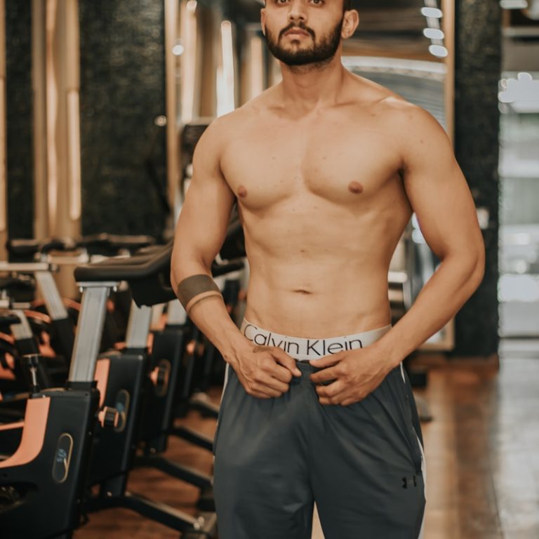 topless man in blue shorts standing on wooden floor