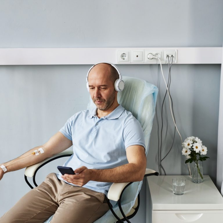 Minimal adult man with headphones during IV drip treatment in clinic